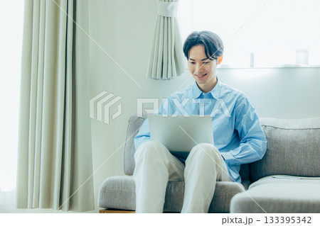 リビングでパソコンを使う若い男性 リビングでパソコンを使う若い男性 133395342