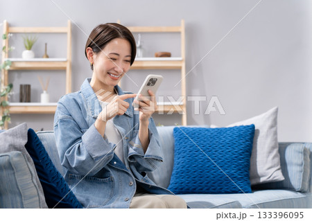 リビングでスマホを操作する女性 133396095