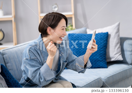 リビングでスマホを持つ女性 応援 リビングでスマホを持つ女性 応援 133396130