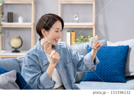 リビングでスマホを持つ女性 応援 リビングでスマホを持つ女性 応援 133396132