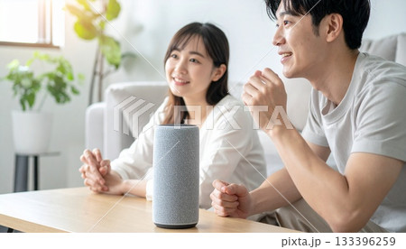 家庭でAIアシスタントに話しかける人物とスマートスピーカーの未来的な日常シーン 133396259