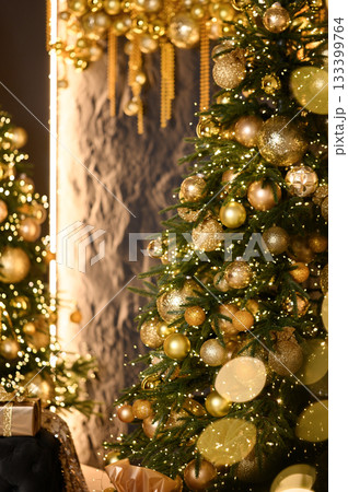 Close-up of a beautifully decorated Christmas tree with golden ornaments, sparkling lights, and festive bokeh in the background. 133399764