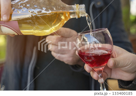 Close-up of hands pouring wine from bottle into glass. Close-up of hands pouring wine from bottle into glass. 133400185