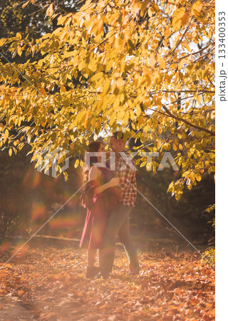 young couple in love hugging in autumn park, glare and sunlight around them young couple in love hugging in autumn park, glare and sunlight around them 133400353