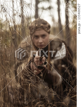 close-up of blonde girl in historical warrior costume, she aims with pistol. 133400527