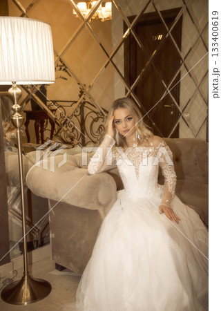 beautiful blonde bride in a long white dress sits in a hotel beautiful blonde bride in a long white dress sits in a hotel 133400619