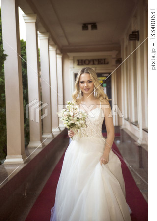 beautiful blonde bride walks along the opened gallery of the hotel with a bouque beautiful blonde bride walks along the opened gallery of the hotel with a bouque 133400631