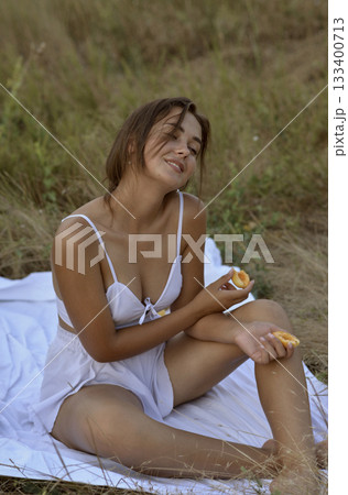 young and beautiful girl in white summer clothes and with tanned skin sits on the field. young and beautiful girl in white summer clothes and with tanned skin sits on the field. 133400713