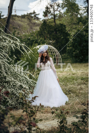 Elegant Bride in a Flowing White Gown Surrounded by Lush Greenery  133400748