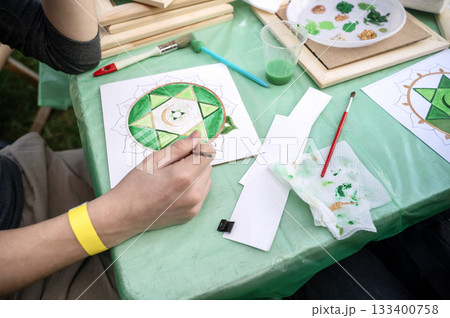 woman's hand draws a mandala with green paints and a brush woman's hand draws a mandala with green paints and a brush 133400758