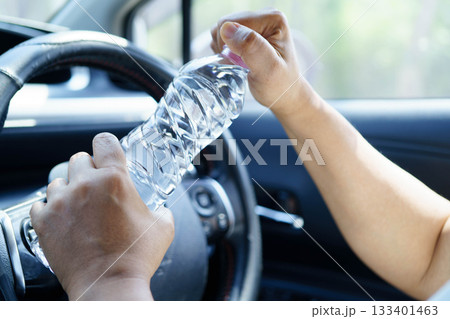 Asian woman driver holding water bottle in car. Asian woman driver holding water bottle in car. 133401463