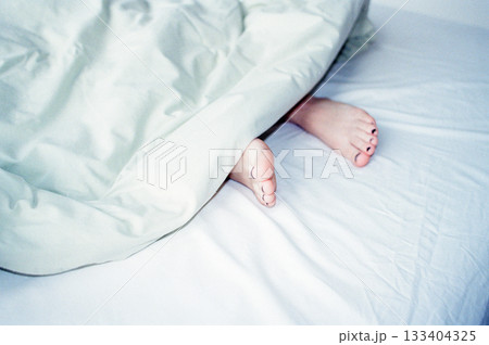 woman's legs are visible from under the blanket. the person is sleeping or resting.  133404325