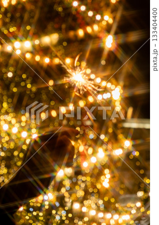 hand holding sparkler in front of Christmas tree. picture shows festive and joyful mood. hand holding sparkler in front of Christmas tree. picture shows festive and joyful mood. 133404400