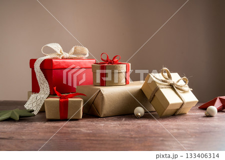 Festive Christmas craft gift boxes with red bows on wooden background Festive Christmas craft gift boxes with red bows on wooden background 133406314