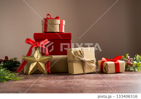 Festive Christmas craft gift boxes with red bows on wooden background Festive Christmas craft gift boxes with red bows on wooden background 133406316
