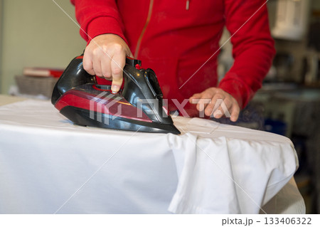Man's hand ironing clothes on an ironing board at home, copy space 133406322