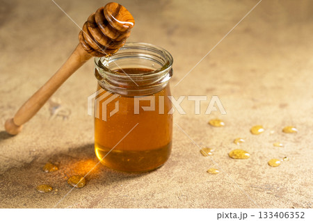 Jar of honey with wooden dipper, sweet liquid, neutral background Jar of honey with wooden dipper, sweet liquid, neutral background 133406352