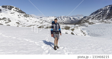 Snow-covered landscape in Leirvassbu, Jotunheimen National Park, with a hiker enjoying the stunning scenery 133408215