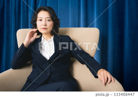 大きな椅子に座るミドルビジネスウーマン 133408447