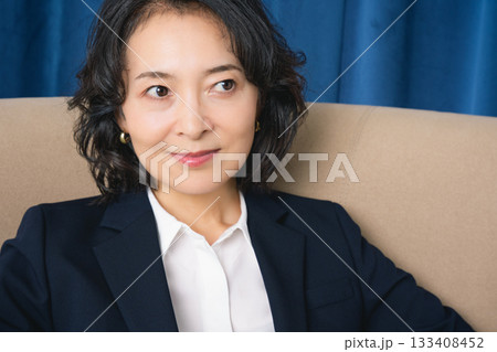 大きな椅子に座るミドルビジネスウーマン 133408452