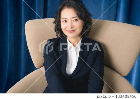 大きな椅子に座るミドルビジネスウーマン 133408456