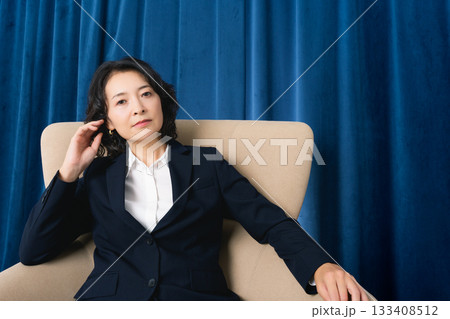大きな椅子に座るミドルビジネスウーマン 133408512