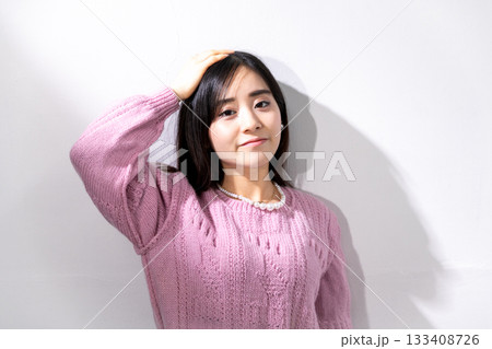 白い壁の前で日差しを浴びながらポーズをとる若い女性 白い壁の前で日差しを浴びながらポーズをとる若い女性 133408726