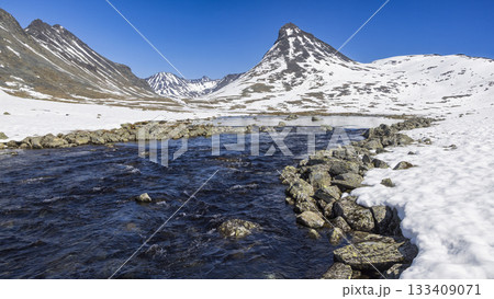 Snow-covered landscape at Leirvassbu in Leirdalen, Jotunheimen National Park showcasing clear skies and a flowing river Snow-covered landscape at Leirvassbu in Leirdalen, Jotunheimen National Park showcasing clear skies and a flowing river 133409071