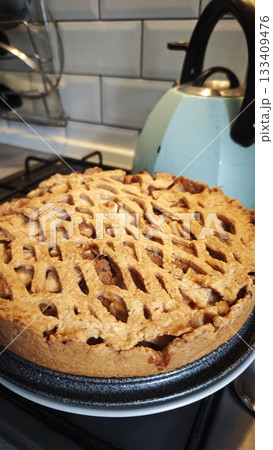 Homemade apple pie with a lattice crust cooling on the stove in a cozy kitchen setting Homemade apple pie with a lattice crust cooling on the stove in a cozy kitchen setting 133409476