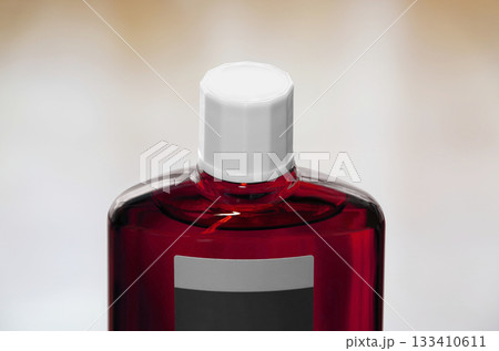 スクリューキャップを閉めた育毛剤の赤色半透明のボトル 133410611