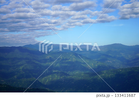 Layers of Green Rolling Hills Under a Bright Blue Sky with Scattered Clouds Layers of Green Rolling Hills Under a Bright Blue Sky with Scattered Clouds 133411687