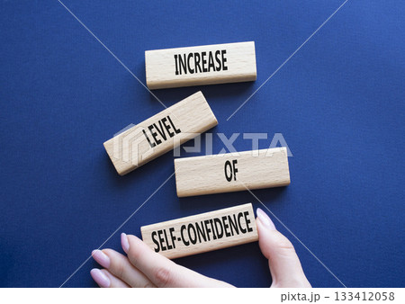 Self-confidence symbol. Wooden blocks with words Increase level of Self-confidence. Beautiful deep blue background. Businessman hand. Business concept. Copy space. Self-confidence symbol. Wooden blocks with words Increase level of Self-confidence. Beautiful deep blue background. Businessman hand. Business concept. Copy space. 133412058