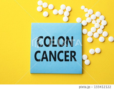 Colon Cancer symbol. Concept word Colon Cancer on blue note. Beautiful yellow background with pills. Medicine and Colon Cancer concept. Copy space Colon Cancer symbol. Concept word Colon Cancer on blue note. Beautiful yellow background with pills. Medicine and Colon Cancer concept. Copy space 133412122