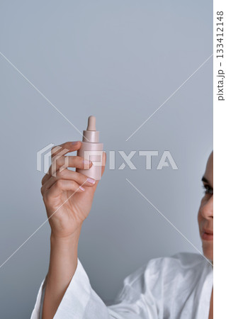 Woman holding skincare serum dropper bottle Woman holding skincare serum dropper bottle 133412148