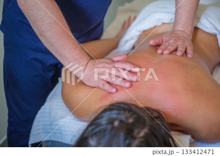 A woman enjoys a soothing back massage from a skilled therapist using oil for relaxation and lymphatic drainage in a spa salon. 133412471