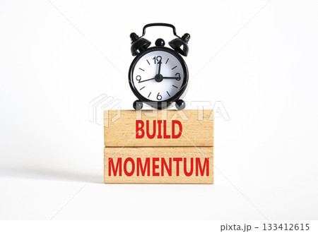 Build momentum symbol. Wooden blocks with words Build momentum. Beautiful white background with alarm clock. Business and Build momentum concept. Copy space. Build momentum symbol. Wooden blocks with words Build momentum. Beautiful white background with alarm clock. Business and Build momentum concept. Copy space. 133412615