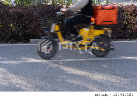 Food delivery rider on yellow electric bike 133413523