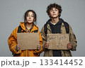 Two young individuals holding signs, expressing a poignant social message. 133414452