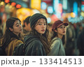 Three young women exploring a vibrant city nightlife, immersed in a lively crowd. 133414513