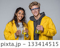 Two young scientists in yellow lab coats holding beakers with colorful liquids. 133414515
