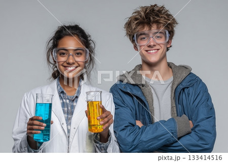 Two young scientists proudly holding colorful liquid samples in a laboratory. 133414516