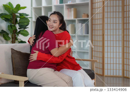 Warm embrace. Two women sharing a joyful hug on a couch. Warm embrace. Two women sharing a joyful hug on a couch. 133414906