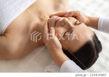 Relaxed young woman receiving gentle face massage at spa, closeup Relaxed young woman receiving gentle face massage at spa, closeup 133414907
