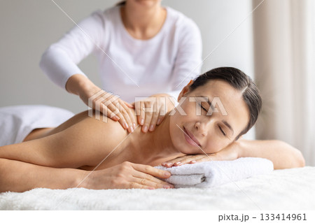 Young woman receiving gentle upper back massage at spa 133414961