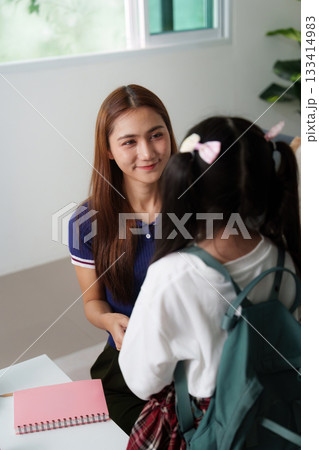 Mother and daughter share a moment before school, exchanging smiles. 133414983