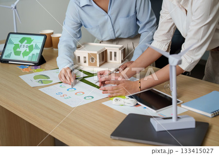 ESG Collaboration. Professionals discussing sustainability strategies with charts and models. 133415027