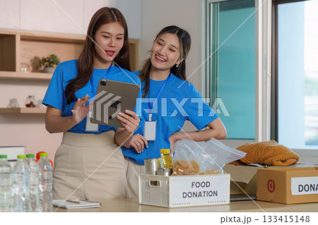 Food Donation Awareness. Volunteers discussing food donation efforts using a tablet. 133415148