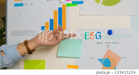 ESG Insights. Close-up of hand analyzing sustainability data on presentation board. ESG Insights. Close-up of hand analyzing sustainability data on presentation board. 133415224