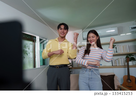 Energetic young couple dancing together during video call 133415253