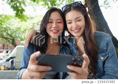 Friendship and Joy. Two young women sharing a delightful moment with coffee outdoors. 133415385